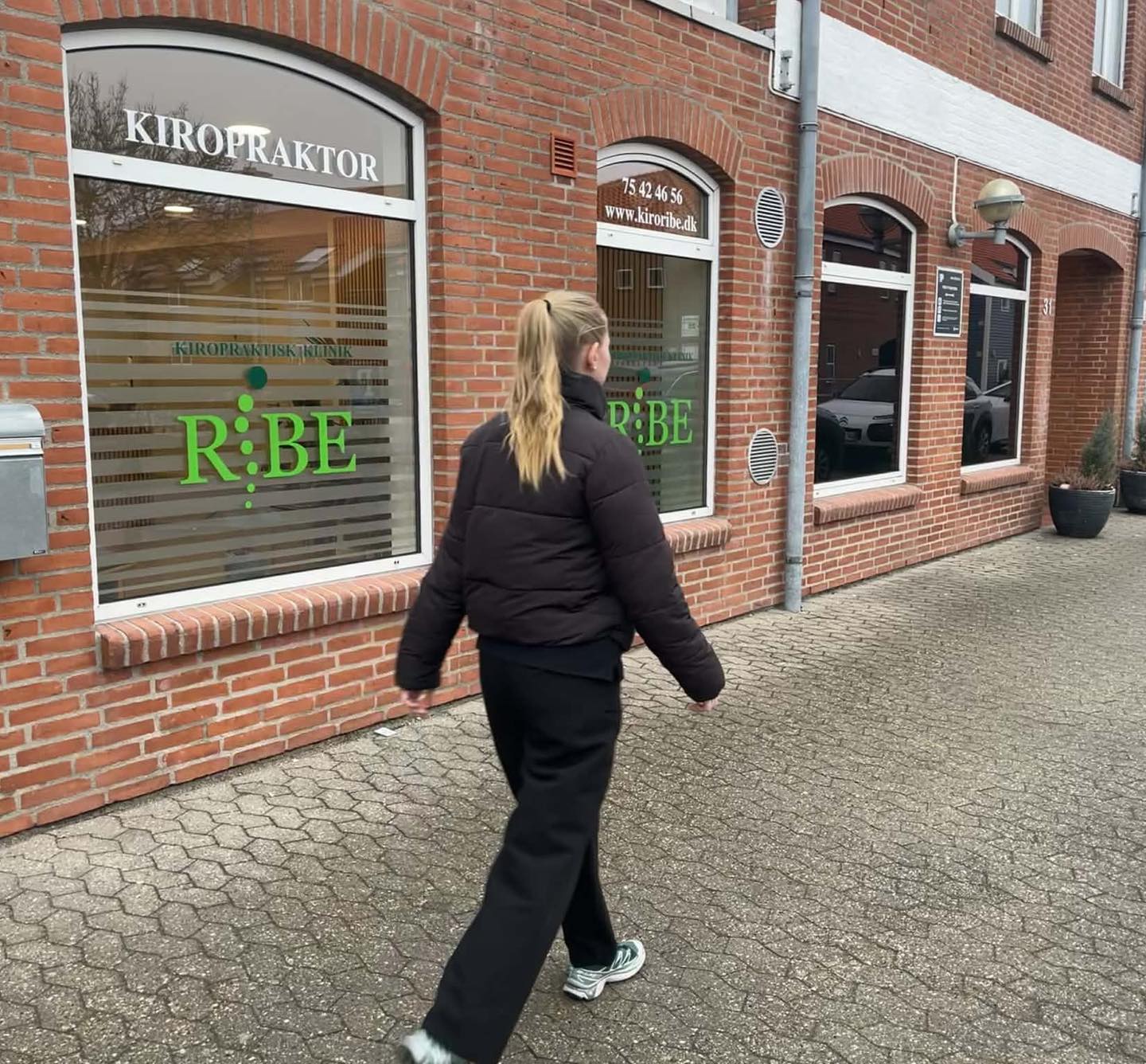 Kiropraktor Karina går udenfor Kiropraktisk Klinik Ribe og opfordrer til bevægelse mod rygsmerter